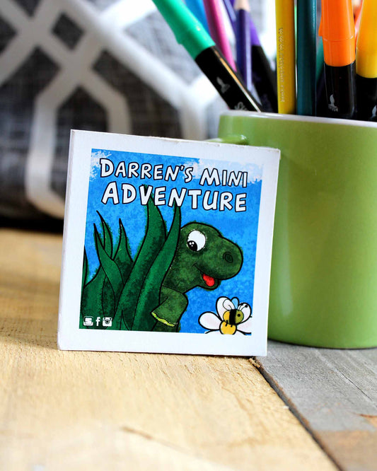 Cartoon turtle with a bee and 'Darren's Mini Adventure' text on a coaster, with markers in the background.