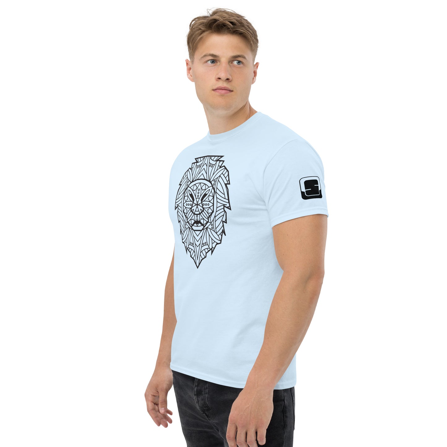 Young man with a focused gaze wearing a light blue t-shirt with a large black geometric lion head design on the chest and a small square logo patch on the sleeve, standing against a white background.