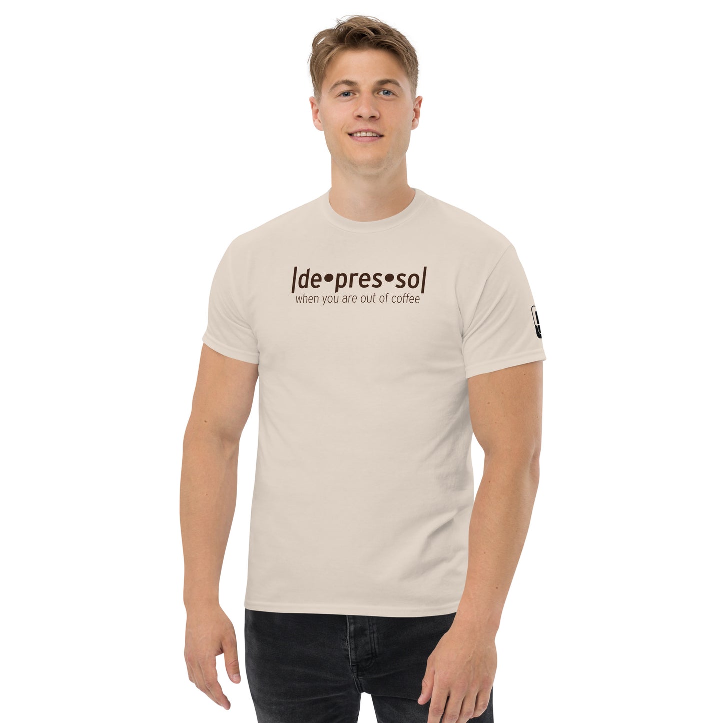 A young man with a friendly demeanor wearing a sand-colored t-shirt that humorously reads 'depresso' with the caption 'when you are out of coffee' underneath in a casual font, complete with a logo patch on the sleeve, against a white background.