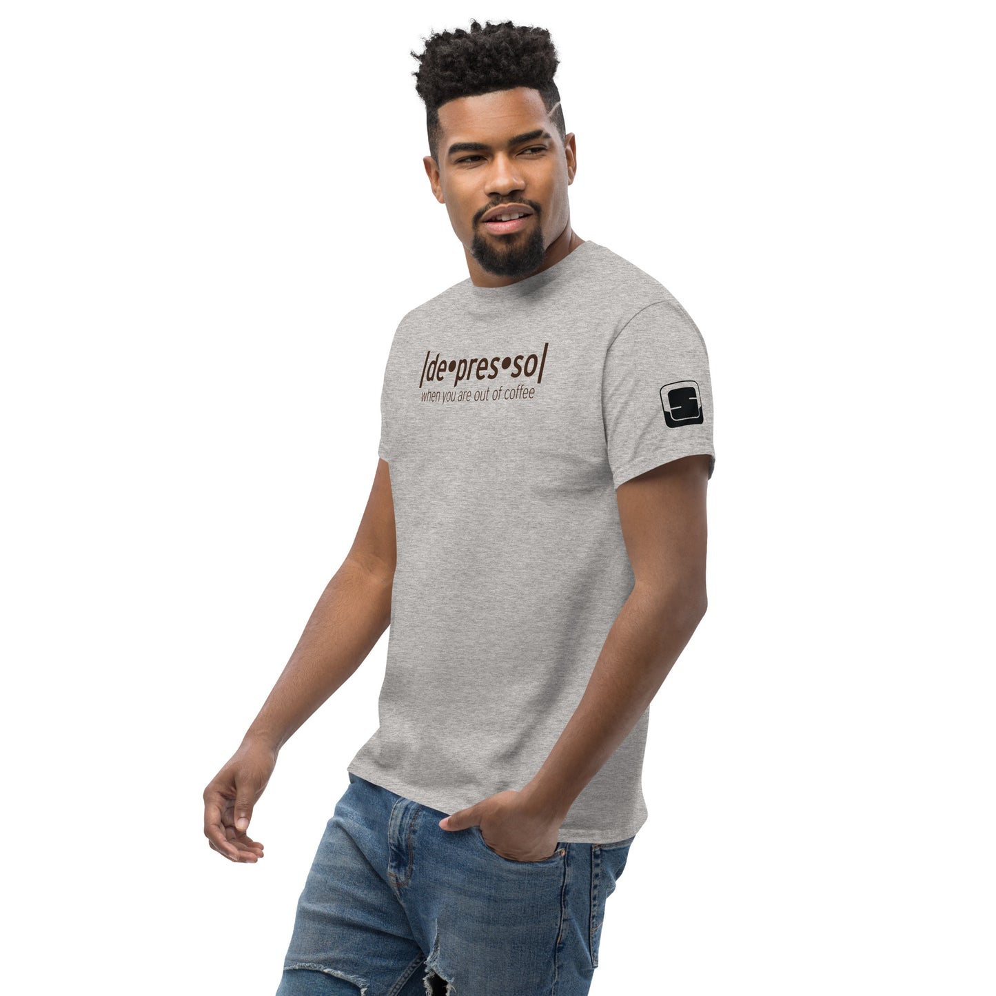 Charming man with a beard, wearing a heather grey t-shirt with the playful words 'depresso' and 'when you are out of coffee' in brown script, a small logo patch on the sleeve, casually posing against a white background