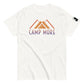 White t-shirt laid flat showcasing the 'CAMP MORE' slogan in purple with an orange mountain range illustration, complete with a black logo patch on the sleeve, isolated on a white background.