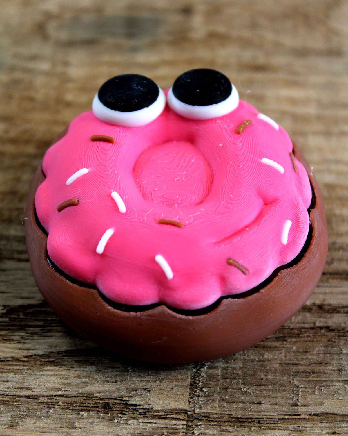 Pink brain-shaped toy with googly eyes on a wooden surface