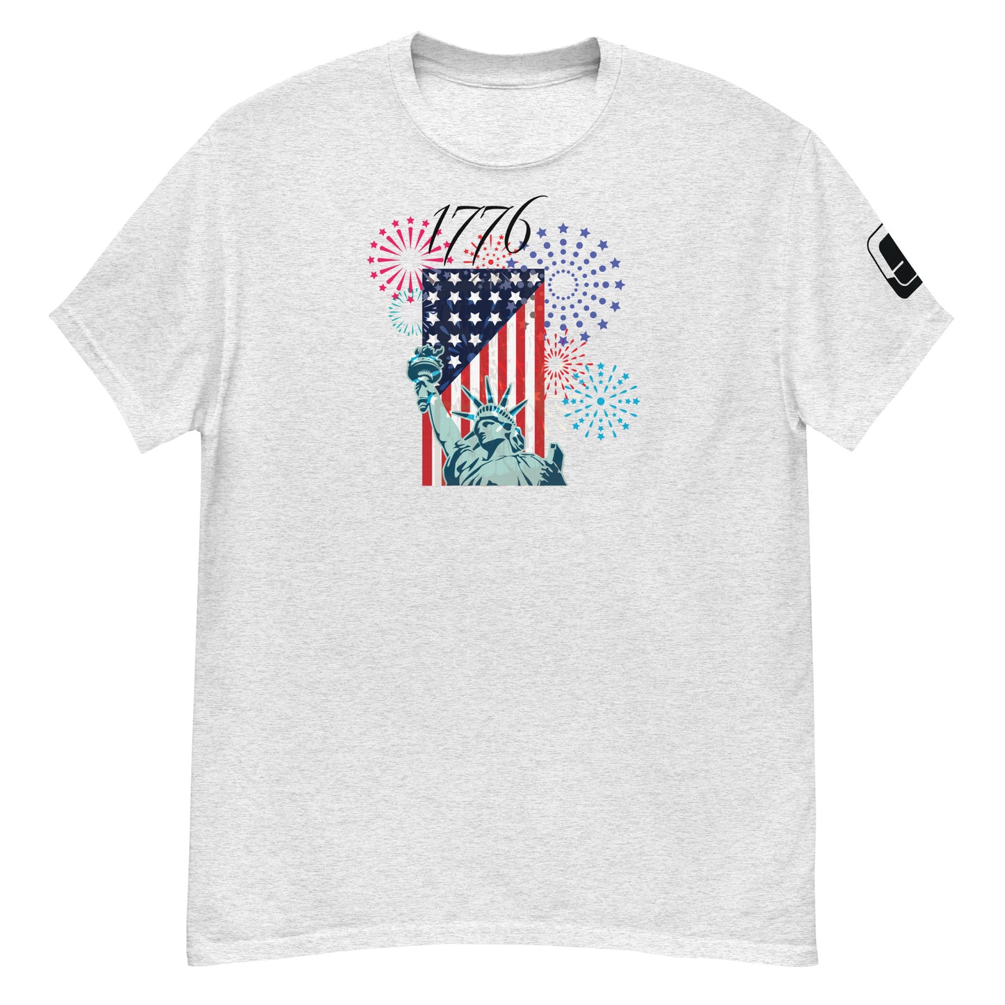 A heather gray t-shirt showcasing a vibrant Fourth of July-themed design. The graphic displays the Statue of Liberty alongside an American flag, with colorful fireworks in red, blue, and purple bursting around it. Above the imagery, the year '1776' is prominently featured in bold numerals, evoking the spirit of American independence.