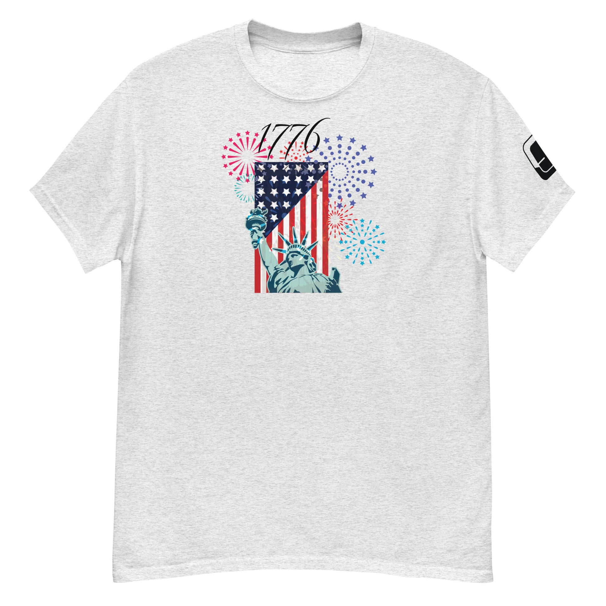 A heather gray t-shirt showcasing a vibrant Fourth of July-themed design. The graphic displays the Statue of Liberty alongside an American flag, with colorful fireworks in red, blue, and purple bursting around it. Above the imagery, the year '1776' is prominently featured in bold numerals, evoking the spirit of American independence.