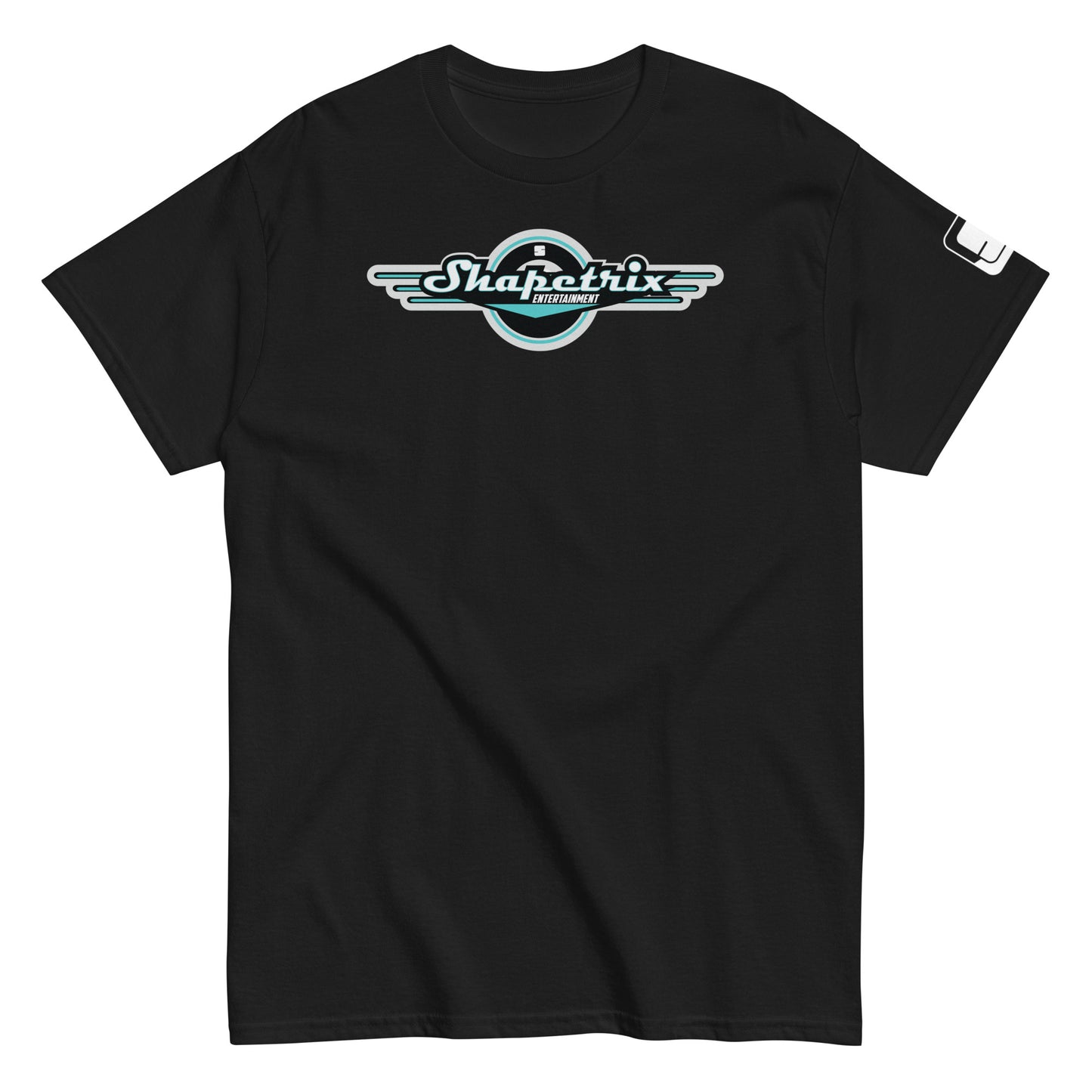 A flat-laid black t-shirt featuring the Shapetrix Entertainment logo prominently on the chest. The logo, designed with stylized white and teal lettering, is framed by a black circular backdrop with wing-like extensions on either side, creating a dynamic, retro-modern look. The left sleeve of the shirt displays a small, rectangular tag with the Shapetrix Entertainment logo, adding an additional branding detail to the garment's sleek and casual design.