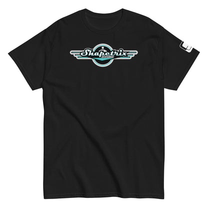 A flat-laid black t-shirt featuring the Shapetrix Entertainment logo prominently on the chest. The logo, designed with stylized white and teal lettering, is framed by a black circular backdrop with wing-like extensions on either side, creating a dynamic, retro-modern look. The left sleeve of the shirt displays a small, rectangular tag with the Shapetrix Entertainment logo, adding an additional branding detail to the garment's sleek and casual design.