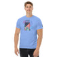 A young man wearing a Carolina blue t-shirt with a festive Fourth of July design. The graphic shows the Statue of Liberty and an American flag, overlaid with colorful fireworks in red, blue, and purple bursts. The design celebrates American independence with '1776' boldly emblazoned across the top.
