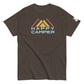 A brown t-shirt featuring an artistic representation of three mountain peaks in red, yellow, and orange colors, overlaid with a stylized blue and light blue "HAPPY CAMPER" text, set against the mountain backdrop. The shirt has a casual fit with a crew neck and short sleeves, suitable for outdoor enthusiasts.