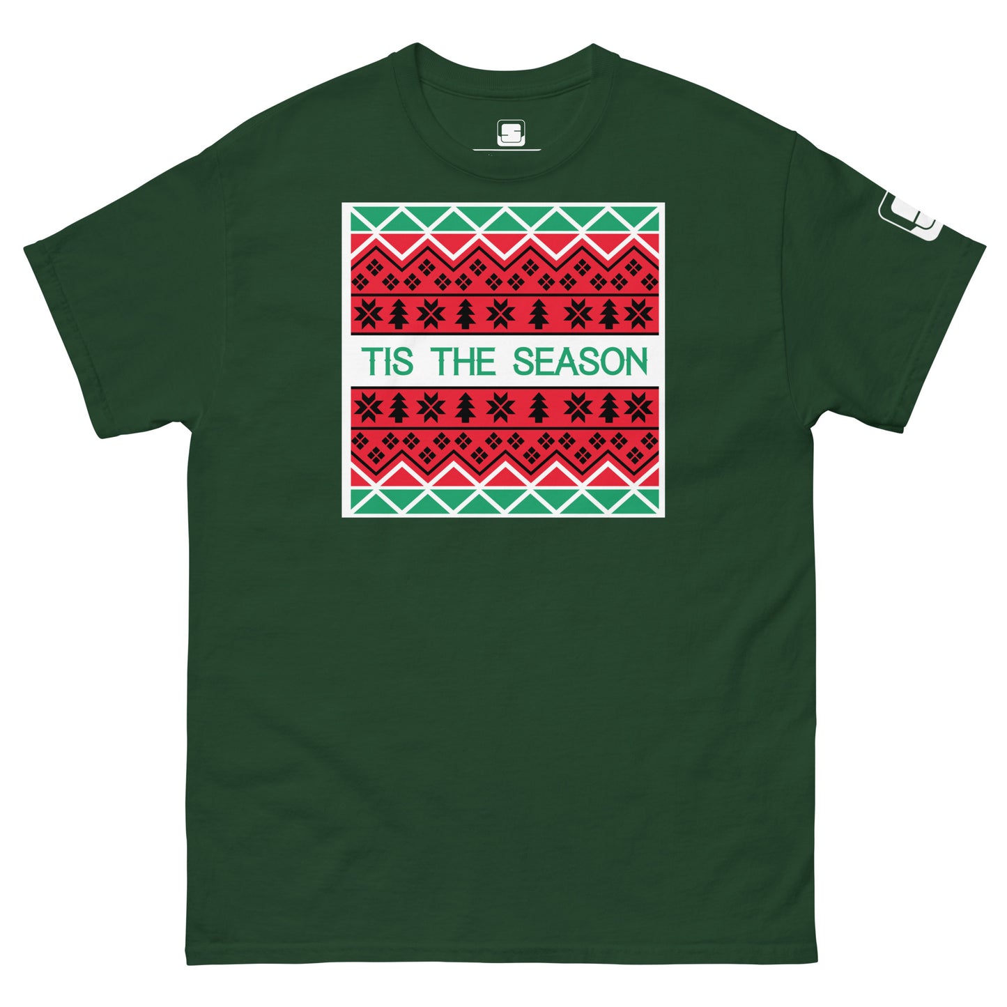A dark green t-shirt featuring a holiday-themed design similar to a Christmas sweater. The central rectangle contains patterns of stars, geometric shapes, and traditional motifs in red, white, and black. The phrase 'TIS THE SEASON' is prominently displayed in bold, green letters on a white background, adding a festive touch to the shirt.