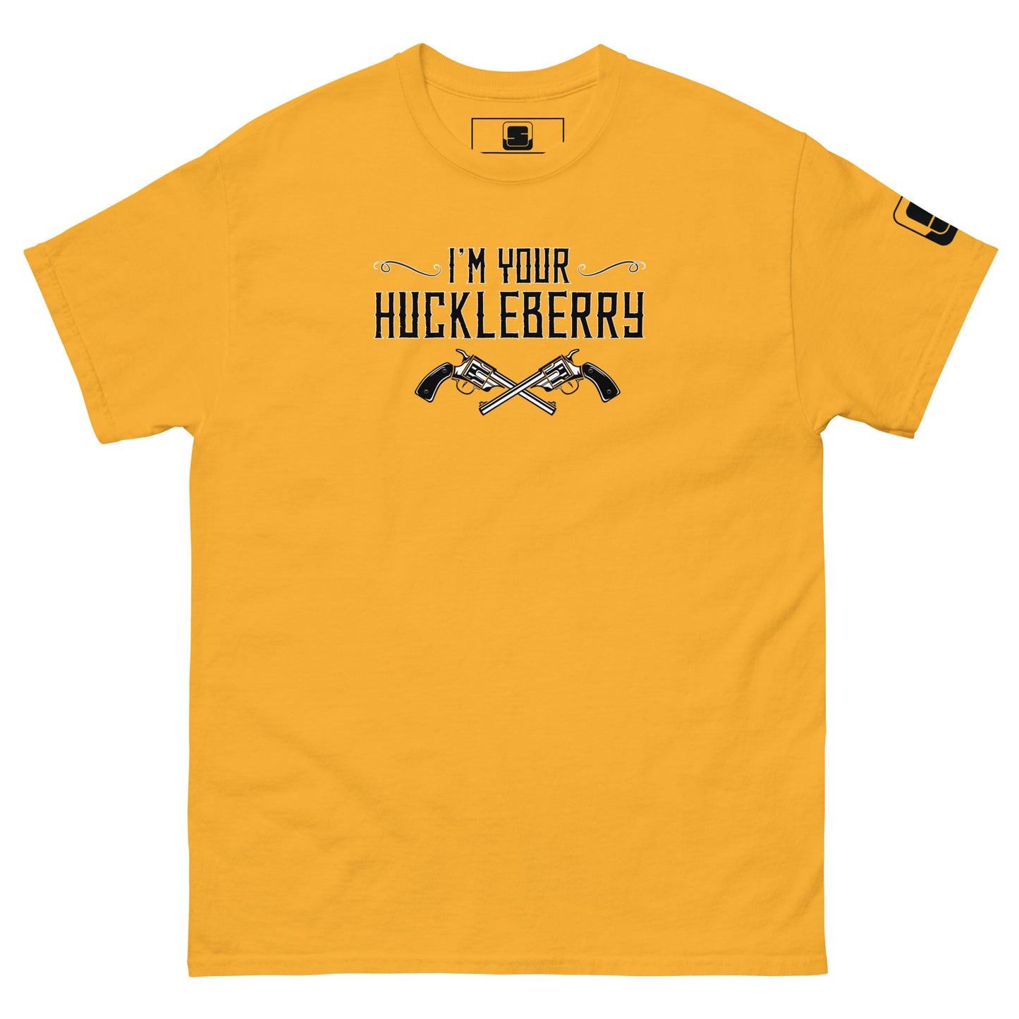 The image shows a golden yellow t-shirt with a black graphic print. The text "I'm Your Huckleberry" is displayed in a stylish, Western-inspired font, underscored by an illustration of two crossed revolvers. The design conveys a bold, adventurous theme reminiscent of classic Western films. A small logo patch is present on the sleeve, adding a modern touch to the shirt's otherwise nostalgic feel.