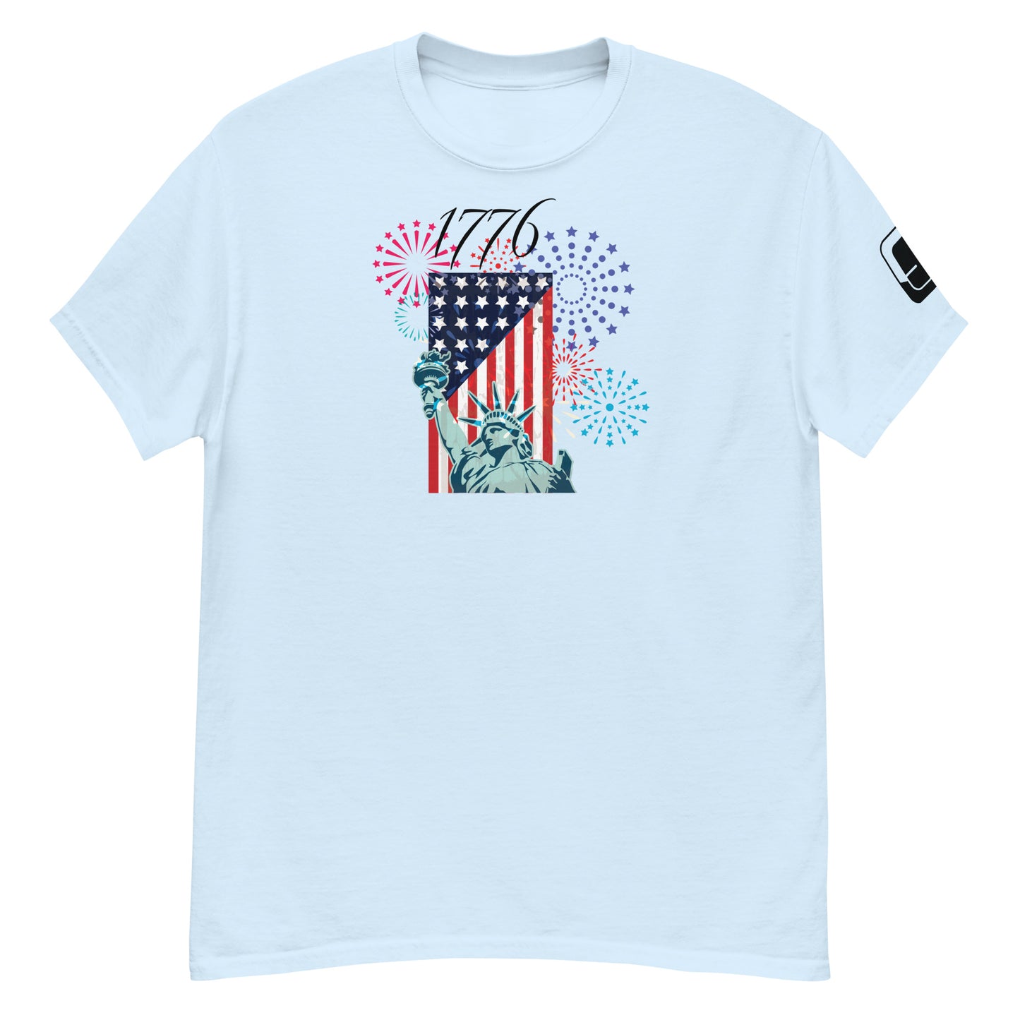 A light blue t-shirt featuring a festive Fourth of July design. The central graphic combines the Statue of Liberty and an American flag, with the year '1776' emblazoned above in a decorative script. The background is filled with vibrant fireworks in red, blue, and purple, symbolizing American independence and celebration.