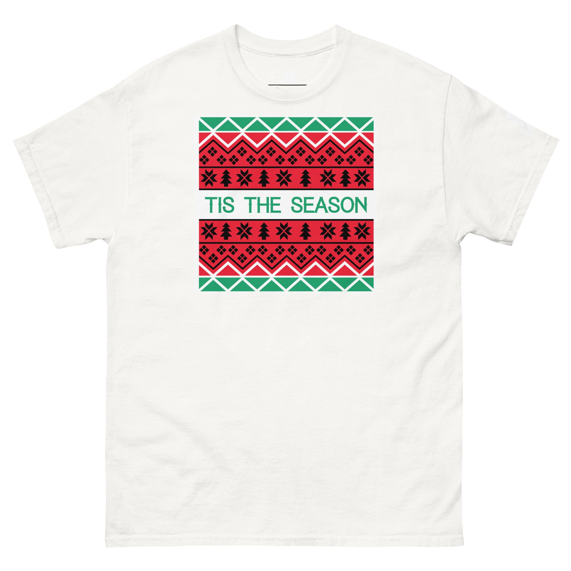 A white t-shirt with a festive, holiday-themed graphic resembling a traditional Christmas sweater design printed in the center. The graphic features multiple rows of red and black patterns, including stars and geometric shapes on a green background. Across the middle, in a contrasting white font, reads the phrase 'TIS THE SEASON', encapsulating the holiday spirit.