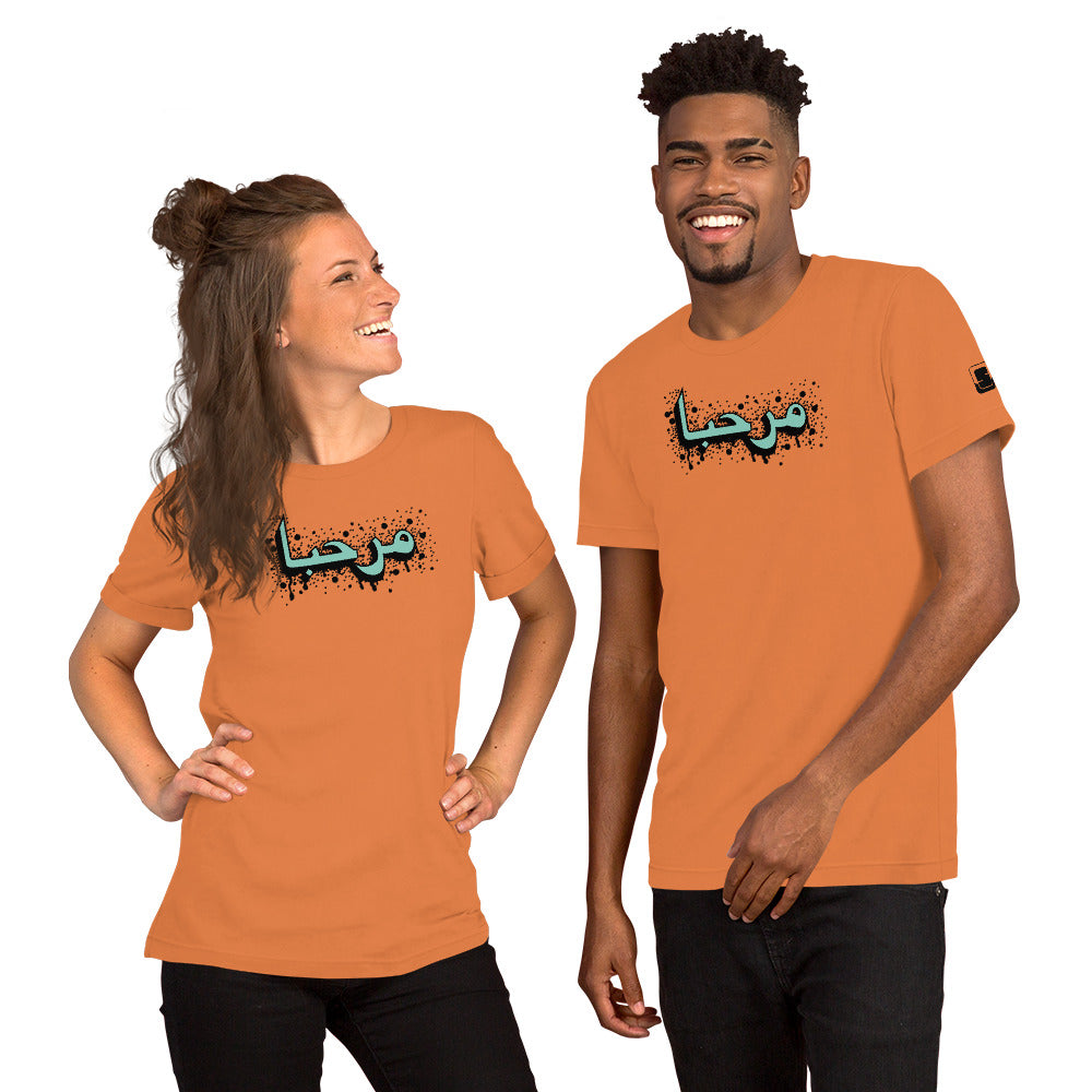 A happy man and woman, both with beaming smiles, wearing matching burnt orange t-shirts with turquoise Arabic calligraphy and black details, each shirt with a small logo patch on the sleeve, posed against a white background.