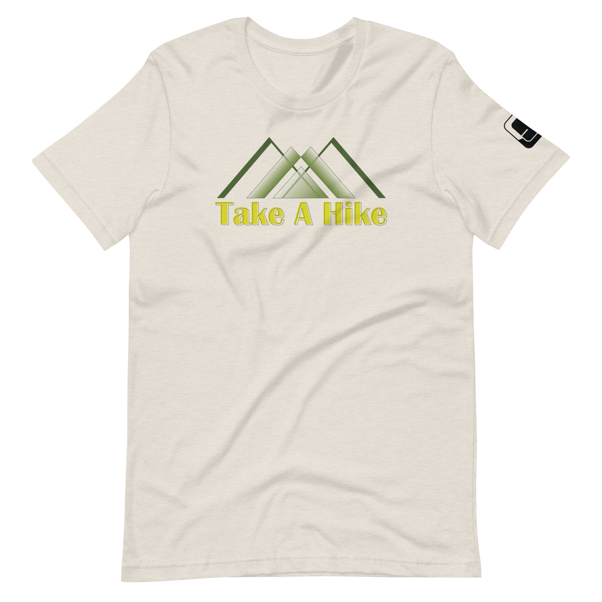 A light cream-colored t-shirt features a central graphic of three overlapping stylized mountain peaks in shades of green, underlined by the phrase "Take A Hike" in bold yellow letters. The shirt has a relaxed fit with a round neckline and short sleeves, sporting a small black logo patch on the right sleeve. The design is placed prominently across the chest, presenting a clear and appealing call to outdoor enthusiasts.