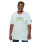 A cheerful African American woman with short, curly hair wears a light gray t-shirt displaying a stylized green mountain graphic with the phrase "Take A Hike" in yellow text. She stands facing the camera with a broad smile, projecting a friendly demeanor. The t-shirt has a relaxed fit and features a small logo patch on the sleeve, emphasizing a casual, outdoor-themed look. She poses against a plain, neutral background that highlights the shirt's design.