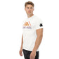 Confident young man in a white t-shirt with 'CAMP MORE' written above an abstrict mountain graphic in orange and purple. There is also a small square logo patch on the sleeve. This shirt is paired with dark trousers, against a white background.